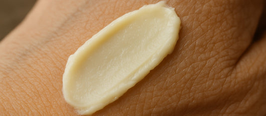 A close-up image of aging skin on the back of a hand with a smooth smear of off-white tallow balm.